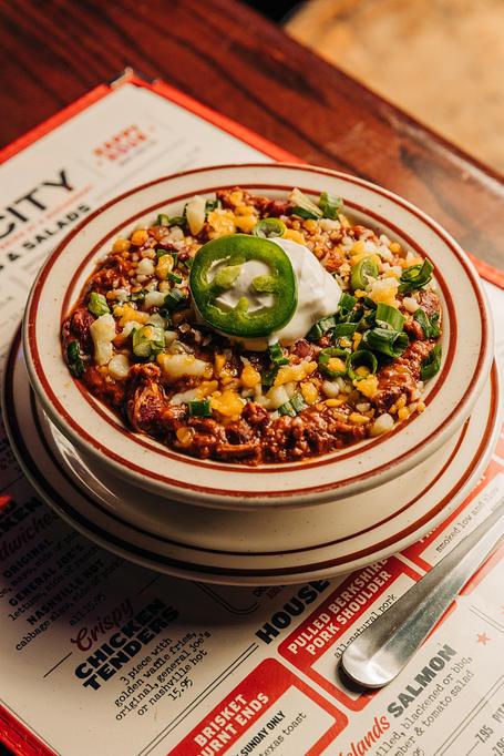 Product: Very full bowl of brisket chili topped with sour cream, cheese, chives and jalapeno slices - Bub City in Rosemont, IL Barbecue Restaurants