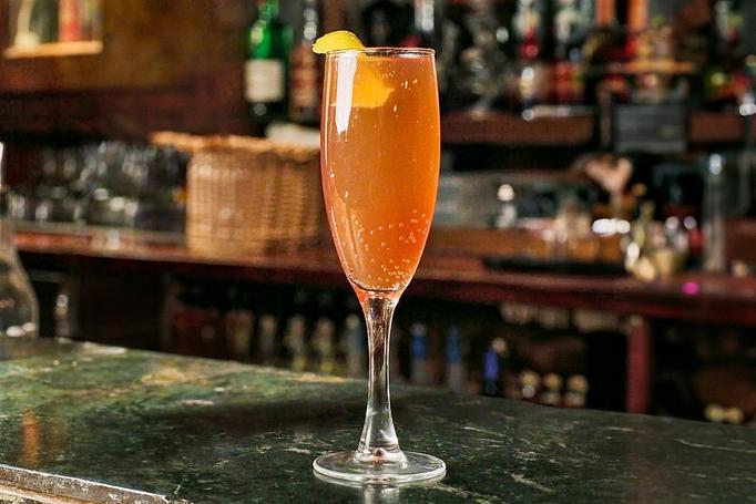 Product: An orange liquid with bubbles in a clear champagne flute, garnished with a lemon peel, on a marbled green bar top - Cafe Ba-Ba-Reeba! in Lincoln Park - Chicago, IL Gluten Free Restaurants