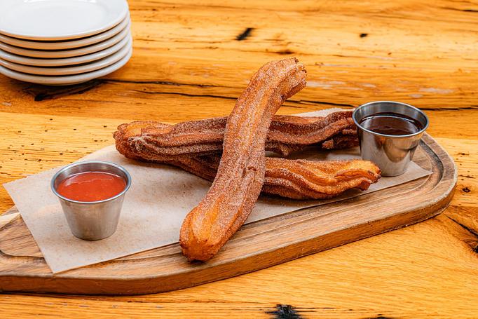 Product: Golden brown churros on a wooden platter with silver containers of red and brown sauce - Cafe Ba-Ba-Reeba! in Lincoln Park - Chicago, IL Gluten Free Restaurants