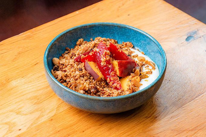 Product: A light blue bowl with golden granola, white yogurt, and fruit topping on a wooden table - Cafe Ba-Ba-Reeba! in Lincoln Park - Chicago, IL Gluten Free Restaurants