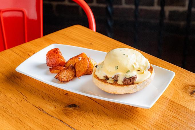 Product: Half of an English muffin, topped with a brown sausage patty, a round poached egg, and a white sauce, served with golden brown potato pieces on a white rectangular plate - Cafe Ba-Ba-Reeba! in Lincoln Park - Chicago, IL Gluten Free Restaurants