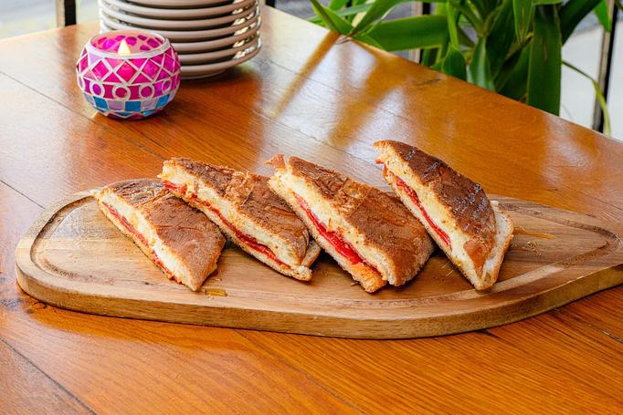 Product: Four triangle-shaped sandwich halves, with bright red filling on a wooden cutting board - Cafe Ba-Ba-Reeba! in Lincoln Park - Chicago, IL Gluten Free Restaurants