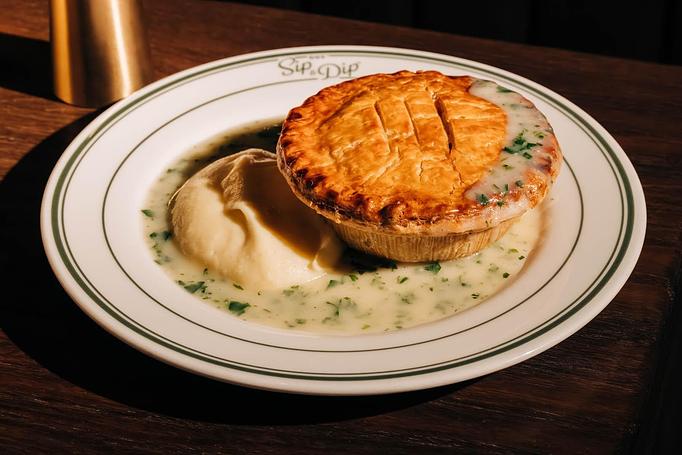 Product: A plate of Pot Pie covered in creamy sauce, accompanied by a serving of mashed potatoes. - Gus' Sip and Dip in Chicago, IL Restaurants/Food & Dining