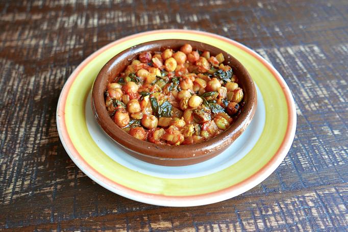 Product: Chickpeas in an orange sauce in a round brown dish, on a wooden table - Cafe Ba-Ba-Reeba! in Lincoln Park - Chicago, IL Gluten Free Restaurants