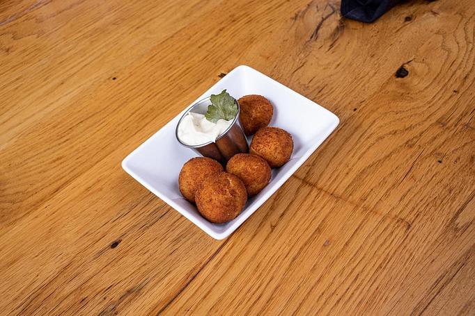 Product: Five golden friend balls in a rectangular white dish with a silver ramekin with white sauce on a wooden table - Cafe Ba-Ba-Reeba! in Lincoln Park - Chicago, IL Gluten Free Restaurants