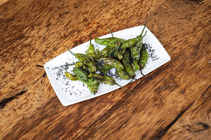 Product: A pile of green peppers on a long, white, rectangular dish, sprinkled with spices and herbs, sitting on a Cafe Ba-Ba-Reeba menu on a wooden table - Cafe Ba-Ba-Reeba! in Lincoln Park - Chicago, IL Gluten Free Restaurants