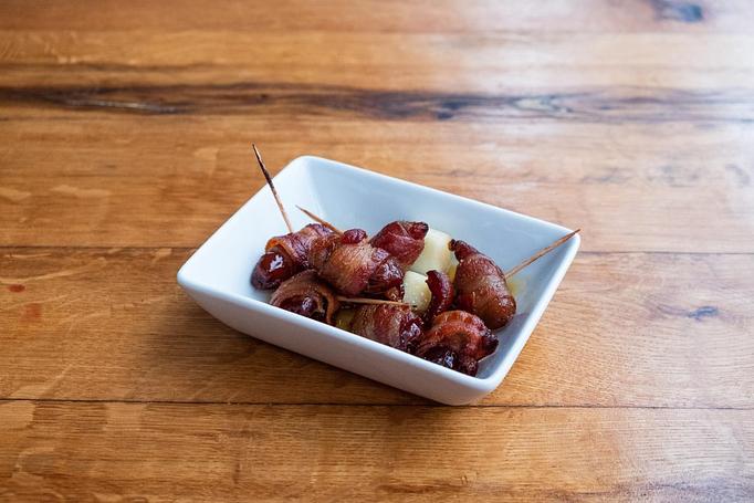 Product: Several brown dates wrapped in brown bacon on toothpicks with apple slices in a small rectangular dish, sitting on a wooden table - Cafe Ba-Ba-Reeba! in Lincoln Park - Chicago, IL Gluten Free Restaurants