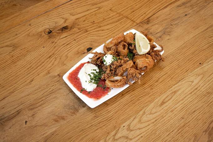 Product: Golden friend calamari pieces served with white sauce and red sauce on a white rectangular plate on a wooden surface - Cafe Ba-Ba-Reeba! in Lincoln Park - Chicago, IL Gluten Free Restaurants