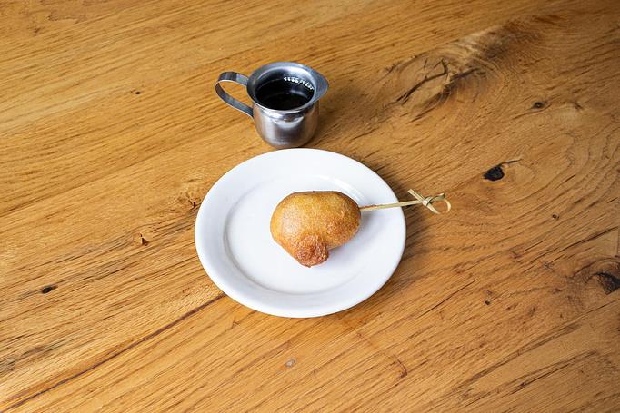 Product: A golden battered piece of chicken on a toothpick on a small white dish, served with a small silver container of syrup on a wooden surface - Cafe Ba-Ba-Reeba! in Lincoln Park - Chicago, IL Gluten Free Restaurants