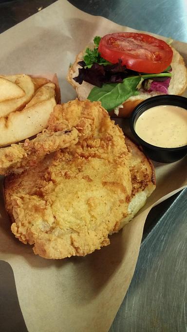 Product: Fried Pork Chop Sandwich with Lettuce, Tomato and Potato Wedges on the side. - Deep Run Roadhouse in West End - Richmond, VA Barbecue Restaurants Product: Fried Pork Chop Sandwich with Lettuce, Tomato and Potato Wedges on the side. - Deep Run Roadhouse in West End - Richmond, VA Barbecue Restaurants