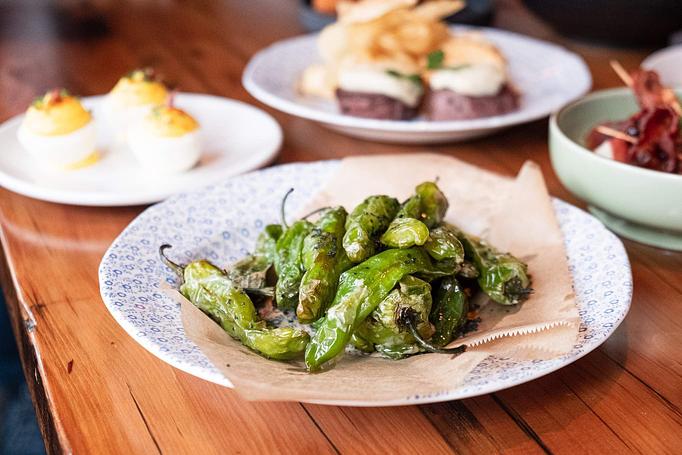 Product: A pile of green peppers on a long, white, rectangular dish, sprinkled with spices and herbs, sitting on a wooden table - Lil’ Ba-Ba-Reeba! in River North - Chicago, IL Bars & Grills