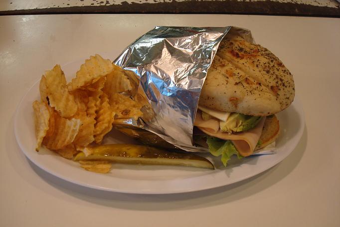 Product: Half Avocado, Sliced Turkey, Lettuce, Tomato, onion, and Provolone Cheese. Served with Chips and a Pickle. - Nutshell Eatery & Bakery in Granbury, TX American Restaurants
