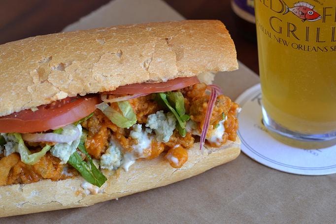 Product: BBQ Oyster Po-Boy - Signature flash-fried oysters, tossed in our famous Crystal hot sauce honey BBQ, served dressed with romaine, tomato, red onion, blue cheese dressing, along with Creole potato salad - Red Fish Grill in French Quarter - New Orleans, LA American Restaurants