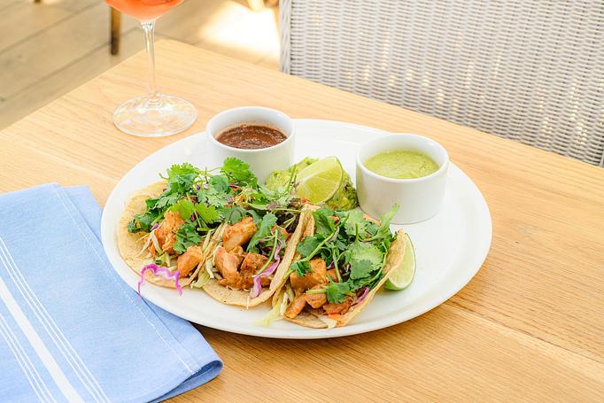 Product: Corn tortilla tacos filled with chicken adobo, slaw, cilantro, and queso fresco served with smoked poblano salsa and pico de gallo on the side, guacamole on the plate, and a lime cheek - Summer House - Las Vegas in Las Vegas, NV Restaurants/Food & Dining