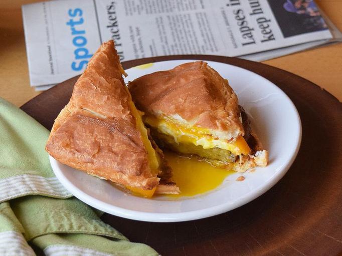 Product: Breakfast Sandwich - Eggs your way, sausage, bacon, or ham, cheddar, on a croissant - West Allis Cheese & Sausage Shoppe in West Allis, WI Coffee, Espresso & Tea House Restaurants