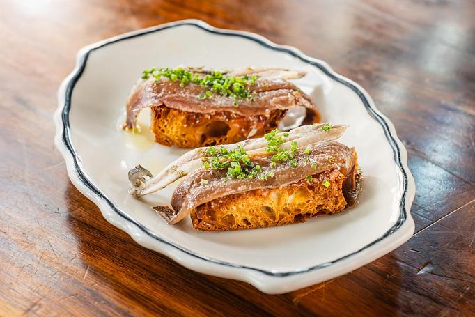 Product: Two pieces of toasted bread topped with a sardine and fresh green herbs on a wooden table - Lil’ Ba-Ba-Reeba! in River North - Chicago, IL Bars & Grills