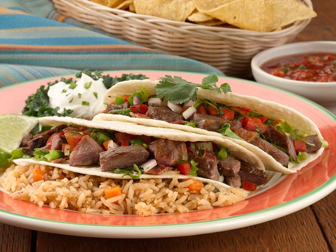 Product: Two flour tortillas with grilled fajita steak or chicken, pico de gallo, freshly chopped cilantro, Monterey and Cheddar cheese and bacon with caramelized onions. Served with a side of Spanish rice, seasoned vegetables, sour cream topping and a lime wedge. - Paradiso Mexican Restaurant in Fargo, ND Mexican Restaurants