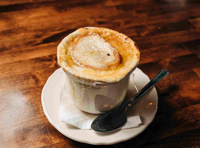 Product: Bowl of French onion soup topped with melted Gruyère cheese in a white bowl - RJ Grunts in Lincoln Park - Chicago, IL American Restaurants