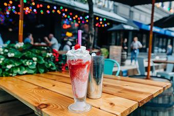 Product: Vanilla milkshake with strawberry swirls served in a frosty glass and topped with whipped cream and a cherry - Bub City in Rosemont, IL Barbecue Restaurants