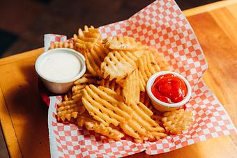 Product: Waffle-style French fries served on red checkered tissue paper with ramekins of ranch dressing and ketchup - Bub City in Rosemont, IL Barbecue Restaurants