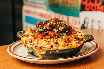 Product: Small black skillet of macaroni and cheese topped with baby back rib meat cut off the bone - Bub City in Rosemont, IL Barbecue Restaurants