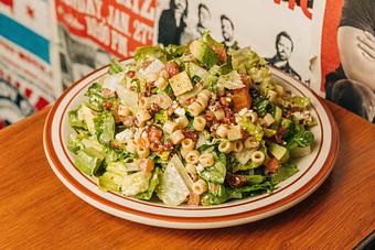 Product: Bowl of lettuce tossed in salad dressing and topped with croutons, tube-shaped pasta, bacon bits and cheese - Bub City in Rosemont, IL Barbecue Restaurants