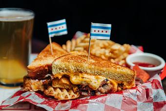 Product: Grilled cheese sandwich cut in half and served on top of red checkered tissue paper with Chicago flag tooth picks stuck into each half of the sandwich - Bub City in Rosemont, IL Barbecue Restaurants