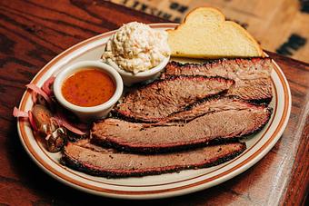 Product: White plate containing slices of brisket meat, a slice of Texas toast, pickled vegetables, a ramekin of BBQ sauce and a ramekin of coleslaw - Bub City in Rosemont, IL Barbecue Restaurants