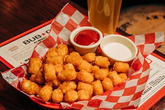 Product: Red basket filled with a pile of crispy tater tots and two ramekins filled with ketcup and ranch dressing - Bub City in Rosemont, IL Barbecue Restaurants