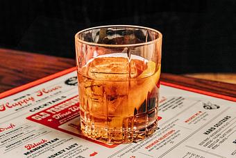 Product: Rocks cocktail glass containing a light brown-colored beverage served with ice and an orange peel slice - Bub City in Rosemont, IL Barbecue Restaurants