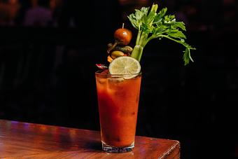 Product: Bloody Mary cocktail served in a pint glass topped with a lime slice, celery stick and skewer of olives, pickles and peppers - Bub City in Rosemont, IL Barbecue Restaurants
