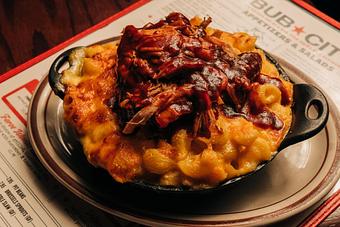 Product: Black skillet bowl filled with macaroni and cheese and topped with saucy pulled pork meat - Bub City in Rosemont, IL Barbecue Restaurants