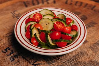 Product: Small bowl filled with cucumber slices and cherry tomatoes - Bub City in Rosemont, IL Barbecue Restaurants