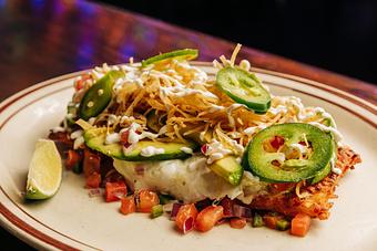 Product: Crispy hash browns topped with eggs, avocado, pico de gallo, tortilla strips, sour cream and cheese served on a white plate - Bub City in Rosemont, IL Barbecue Restaurants