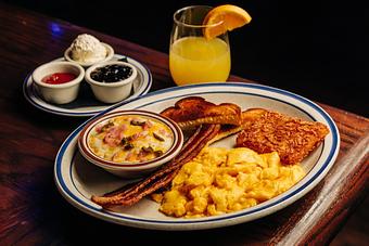 Product: Large plate containing scrambled eggs, hash browns, two slices of bacon, two slices of toast and a small bowl of grits - Bub City in Rosemont, IL Barbecue Restaurants