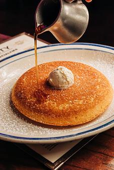 Product: Large, fluffy pancake topped with butter and powered sugar with syrup being poured on top - Bub City in Rosemont, IL Barbecue Restaurants