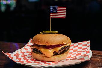 Product: Cheeseburger on a plate with red checkered tissue paper and an American flag toothpick in the top bun - Bub City in Rosemont, IL Barbecue Restaurants