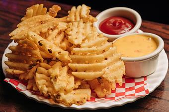 Product: Waffle-style French fries on a plate with cheese and ketchup - Bub City in Rosemont, IL Barbecue Restaurants