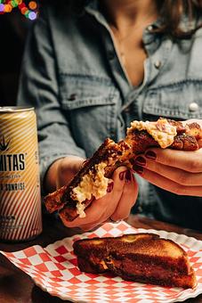Product: Person holding a grilled cheese sandwich with a canned beverage to the left - Bub City in Rosemont, IL Barbecue Restaurants