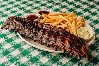 Product: Full slab of ribs served with french fries on a white oval plate on top of a table with a green checkered tablecloth. - RJ Grunts in Lincoln Park - Chicago, IL American Restaurants