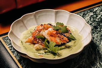 Product: A dish featuring grilled prawns on a bed of green curry sauce, garnished with fresh herbs, served in a scalloped white bowl. - Crying Tiger in Chicago, IL Restaurants/Food & Dining