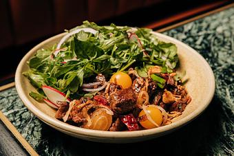Product: A bowl of colorful stir-fry featuring cherry tomatoes, onion slices, cilantro, and assorted vegetables served on a dark plate. - Crying Tiger in Chicago, IL Restaurants/Food & Dining