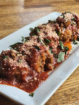 Product: Italian sausage meatballs cooked in a bolognese "Sunday Sauce" (red wine and marinara), topped with parmesan, bread crumbs,
and basil. - Harvey's Grill and Bar in Saginaw, MI American Restaurants
