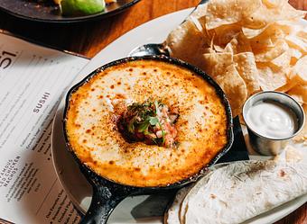 Product: chihuahua cheese broiled to a golden crust. topped with chorizo, green hatch chilies, pico de gallo. served with tortilla chips, crema and warm flour tortillas - Hub 51 in River North - Chicago, IL American Restaurants