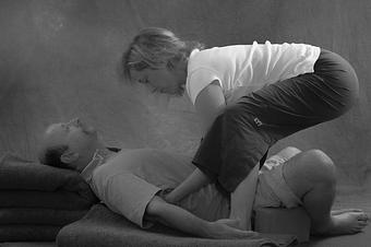 Product: Mary adjusting Slavko in Reclining Supported Baddha Konasana. - Awakening Point Yoga Studio in Hackettstown, NJ Yoga Instruction