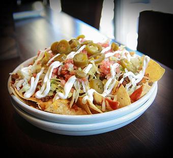 Product: Fresh tortilla chips piled high with melted cheddar cheese, refried beans, diced tomatoes and shredded lettuce. Topped with taco sauce, sour cream, jalapenos, and your choice of chicken or beef. - Big Whiskey's American Restaurant & Bar in Ozark, MO American Restaurants