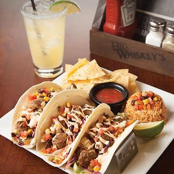 Product: Seasoned steak tips served in three soft flour tortillas over a blend of shredded lettuce and red cabbage, topped with black bean corn salsa and sriracha sour cream. Served with Spanish rice and chips and salsa. - Big Whiskey's American Restaurant & Bar in Springfield, MO American Restaurants