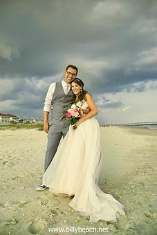 Product: Bride and Groom posing for the camera with dark clouds in the background at Ocean Isle Beach, NC - Billy Beach Photography in The Kerridor - Wilmington, NC Photography
