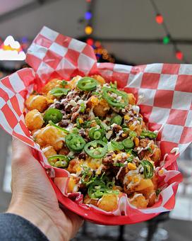 Product: Tater tots served in a red basket on top of red checkered tissue paper and topped with chili, jalapeno slices and cheese - Bub City in Rosemont, IL Barbecue Restaurants