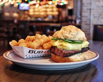 Product: Brisket sandwich served on a biscuit and topped with egg and jalapenos, served with a cardboard boat of waffle-style French fries - Bub City in Rosemont, IL Barbecue Restaurants